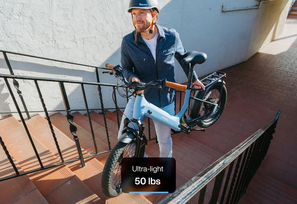 A person carrying a Lightweight Fat Tire eBike, highlighting its ultra - light weight of 50 lbs.