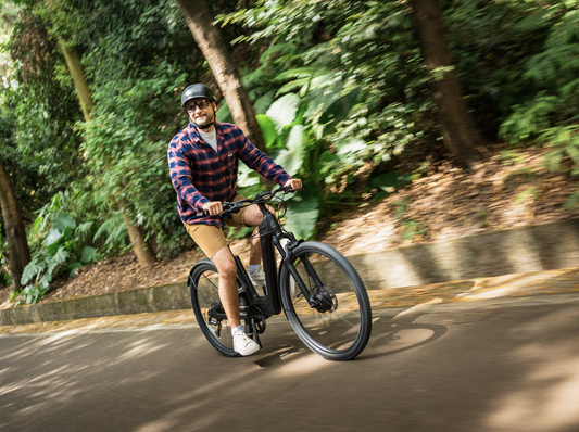 A man is riding a black carbon fiber dual-motor electric bicycle on a city road