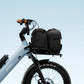 Black front cargo rack on an e-bike, loaded with two black bags, demonstrating its utility for commuting. 